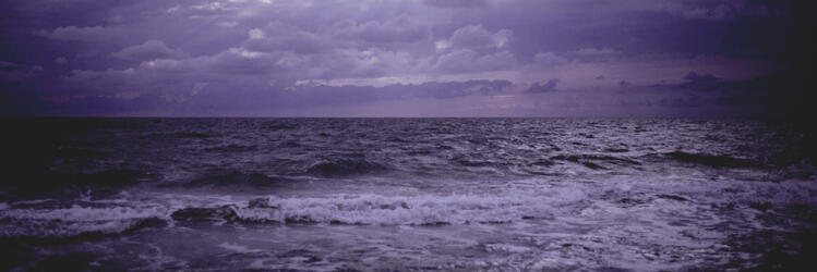 a photograph of the stormy sea, edited to be purple in hue.